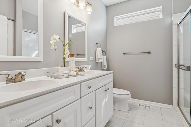 bathroom featuring toilet, tile patterned flooring, a shower with door, and vanity