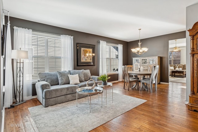 living room featuring wood-type flooring and ceiling fan with notable chandelier