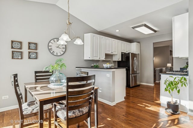 dining space with dark hardwood / wood-style flooring, lofted ceiling, and a notable chandelier