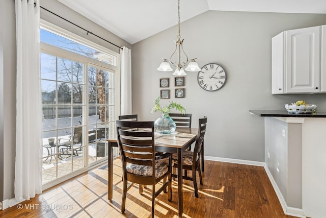 dining room with hardwood / wood-style floors, lofted ceiling, and an inviting chandelier