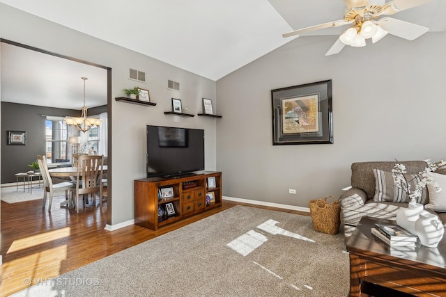 living room with vaulted ceiling, ceiling fan with notable chandelier, and carpet floors