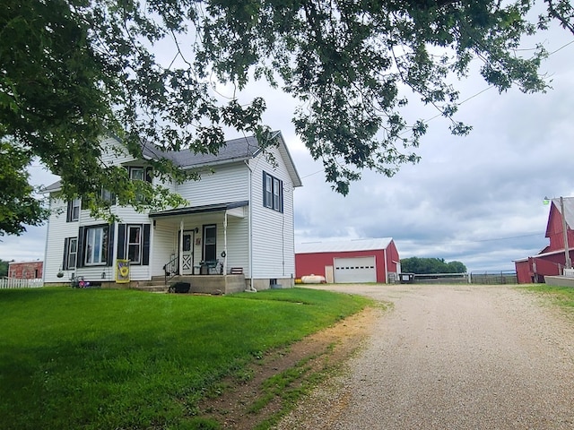 view of front of property featuring an outbuilding, a front lawn, covered porch, and a garage