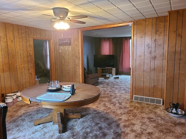 dining room with wooden walls, carpet, and ceiling fan