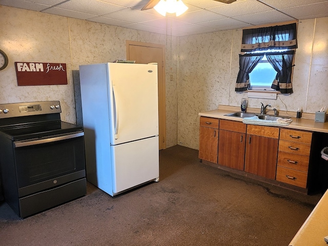 kitchen featuring dark carpet, a drop ceiling, sink, white refrigerator, and stainless steel electric range