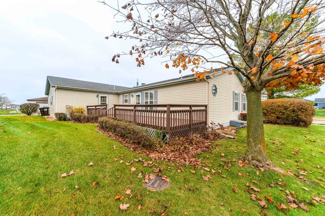 back of property featuring a lawn and a deck