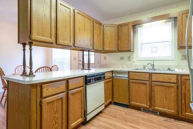 kitchen featuring kitchen peninsula, white dishwasher, light hardwood / wood-style floors, and sink