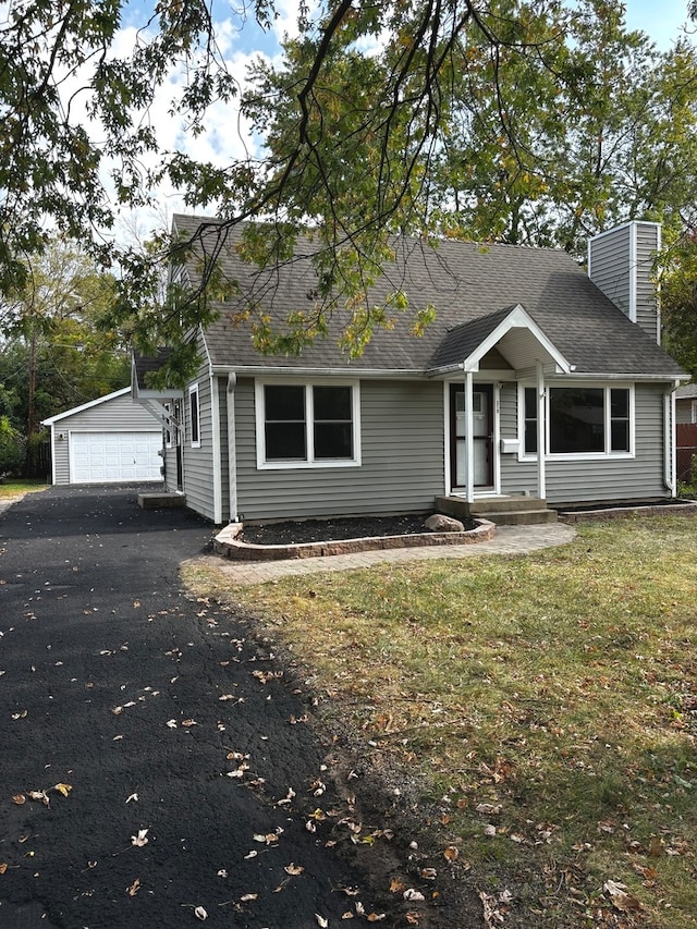 view of front facade featuring a garage, an outbuilding, and a front lawn