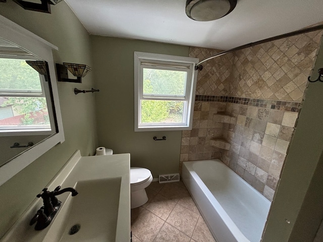 full bathroom featuring tile patterned flooring, toilet, tiled shower / bath, and sink