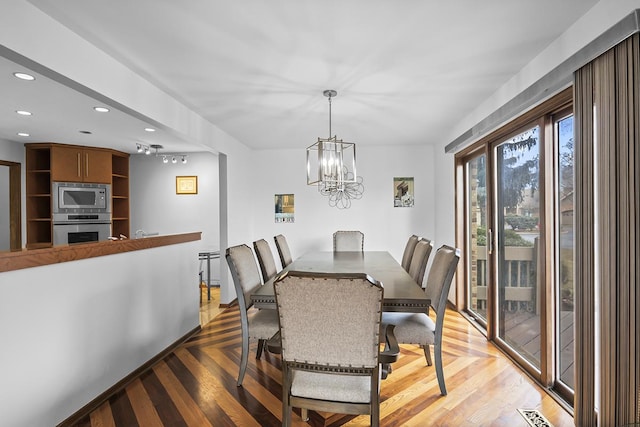 dining area with hardwood / wood-style floors and a notable chandelier