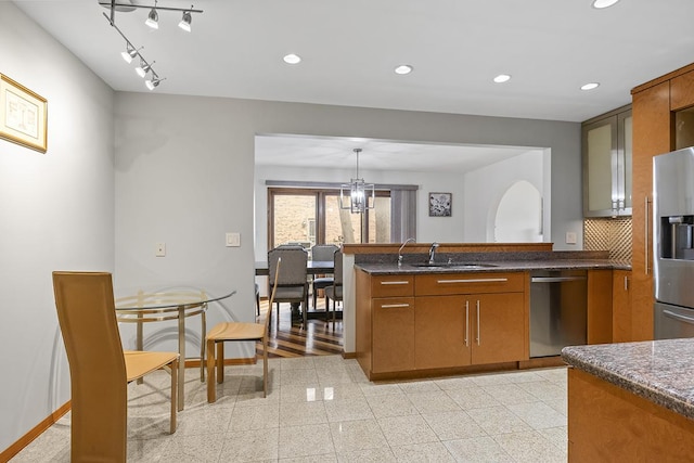 kitchen featuring appliances with stainless steel finishes, backsplash, sink, a notable chandelier, and hanging light fixtures