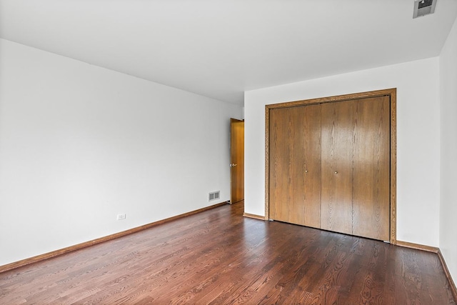 unfurnished bedroom featuring dark hardwood / wood-style flooring and a closet