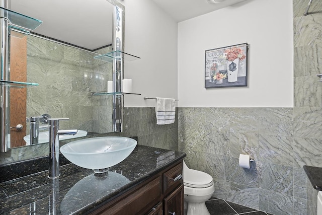 bathroom featuring a tile shower, vanity, toilet, and tile walls