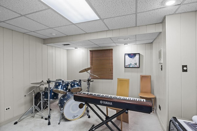 misc room with a paneled ceiling and wooden walls