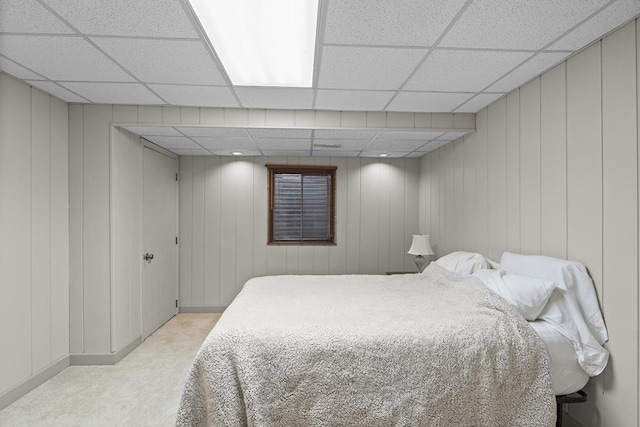 carpeted bedroom featuring a drop ceiling and wooden walls