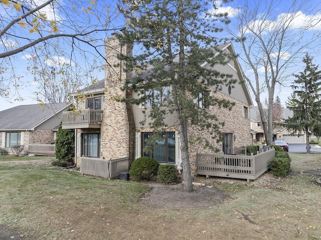 rear view of house featuring a balcony and a yard