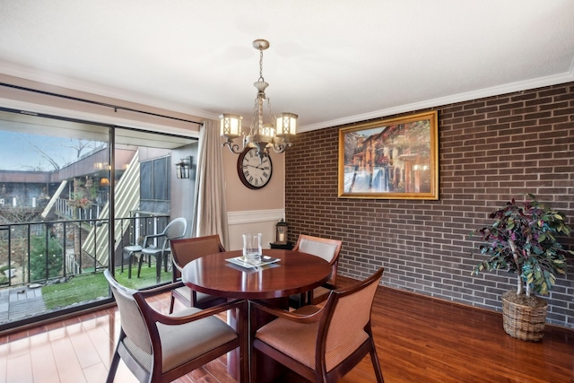 dining room featuring a chandelier, dark hardwood / wood-style floors, ornamental molding, and brick wall