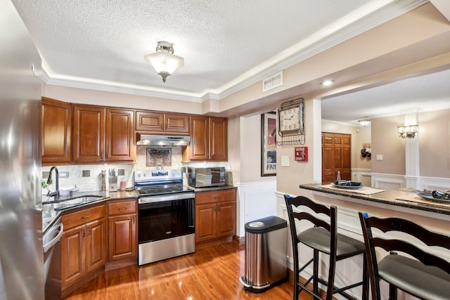 kitchen featuring ornamental molding, sink, light wood-type flooring, and appliances with stainless steel finishes