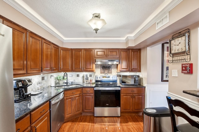 kitchen with sink, tasteful backsplash, light hardwood / wood-style flooring, a textured ceiling, and appliances with stainless steel finishes