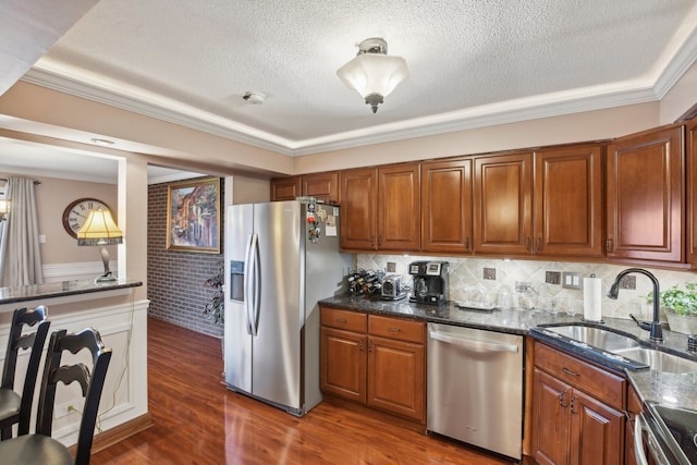 kitchen featuring dark stone counters, sink, ornamental molding, appliances with stainless steel finishes, and dark hardwood / wood-style flooring