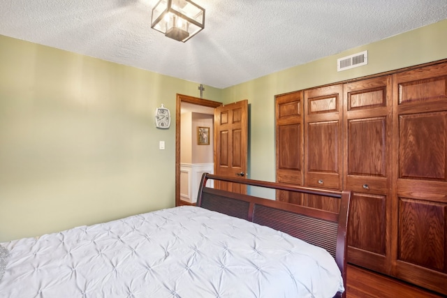 bedroom with a textured ceiling, light hardwood / wood-style flooring, and a closet