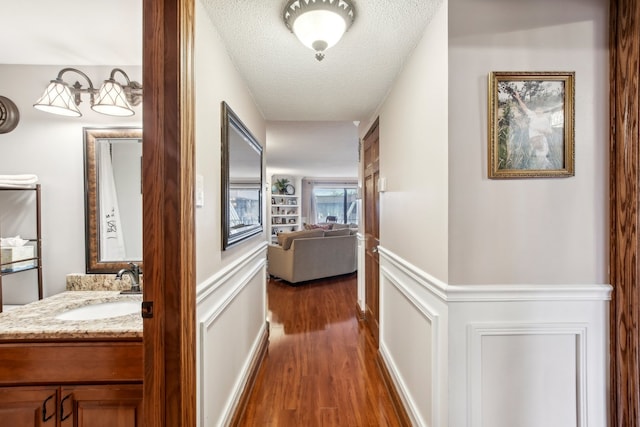 hallway with a textured ceiling, sink, and dark hardwood / wood-style floors