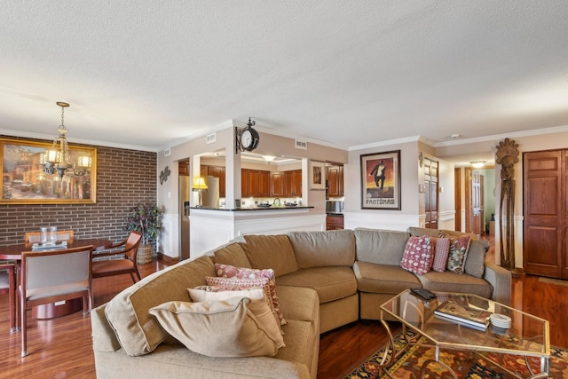 living room featuring hardwood / wood-style floors, a textured ceiling, an inviting chandelier, and ornamental molding