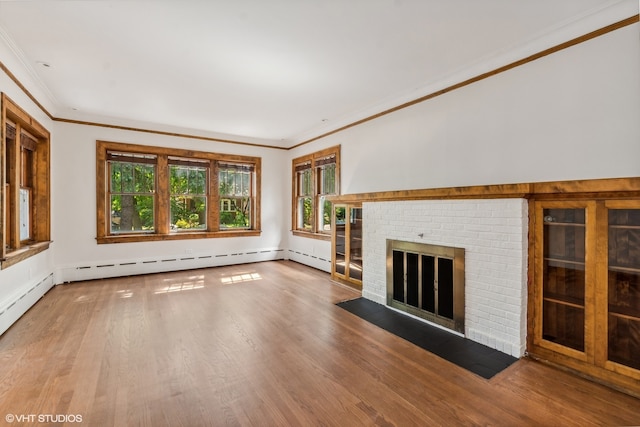 unfurnished living room with crown molding, wood-type flooring, a fireplace, and a baseboard heating unit