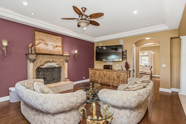 living room featuring ceiling fan, crown molding, a high end fireplace, and dark wood-type flooring