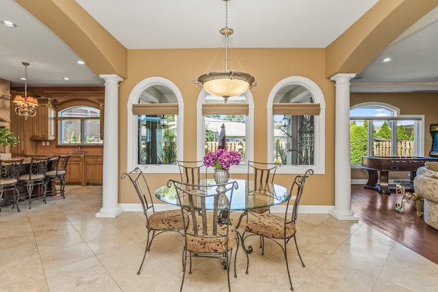 dining area with decorative columns, light hardwood / wood-style flooring, a healthy amount of sunlight, and a notable chandelier