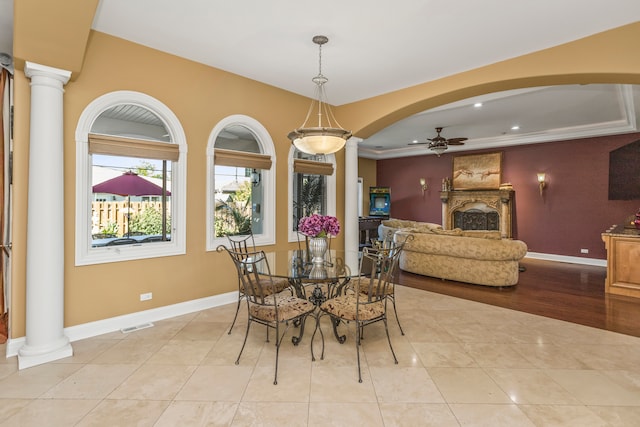 dining space with light wood-type flooring, ornate columns, ceiling fan, and ornamental molding