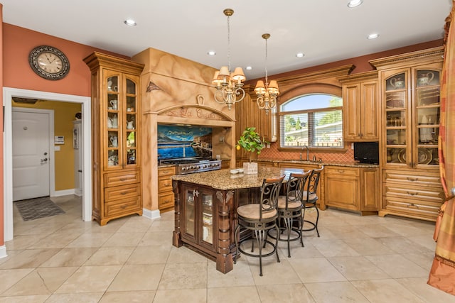 kitchen with decorative backsplash, light stone counters, sink, light tile patterned floors, and a center island