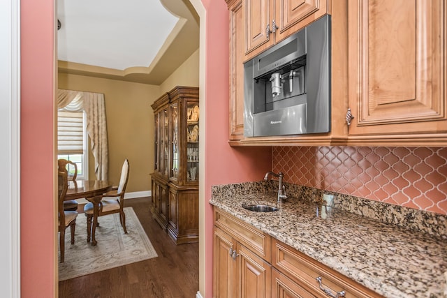 kitchen with light stone countertops, dark hardwood / wood-style flooring, backsplash, and sink