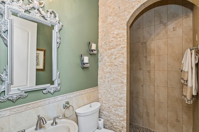 bathroom featuring sink, toilet, tile walls, and tiled shower