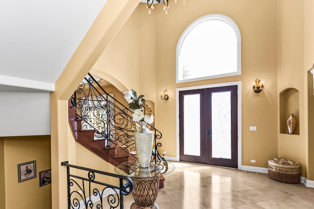 entryway featuring a towering ceiling and french doors