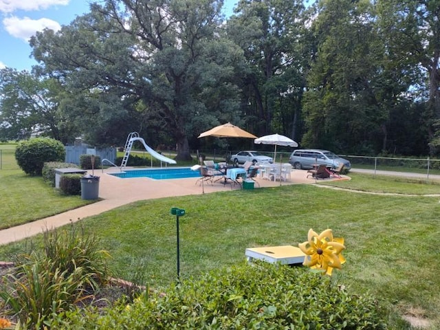 view of swimming pool with a lawn and a water slide