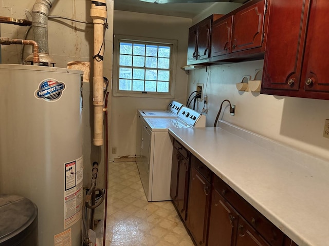 washroom with cabinets, washing machine and dryer, and water heater