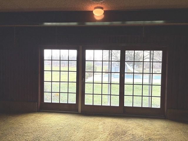 doorway with a textured ceiling and carpet floors