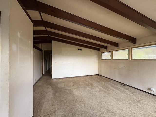 empty room featuring lofted ceiling with beams and light carpet