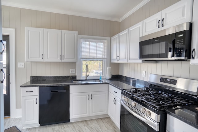 kitchen featuring dark stone counters, ornamental molding, stainless steel appliances, sink, and white cabinets