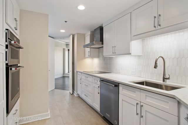 kitchen with white cabinetry, sink, wall chimney exhaust hood, stainless steel appliances, and tasteful backsplash