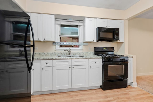937 E 148th St, Dolton, IL 60419 - kitchen with black appliances, white cabinetry, light stone counters, and light wood-type flooring