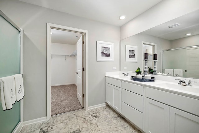 bathroom featuring a shower with door and vanity