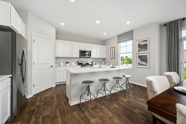 kitchen featuring stainless steel appliances, dark wood-type flooring, and an island with sink