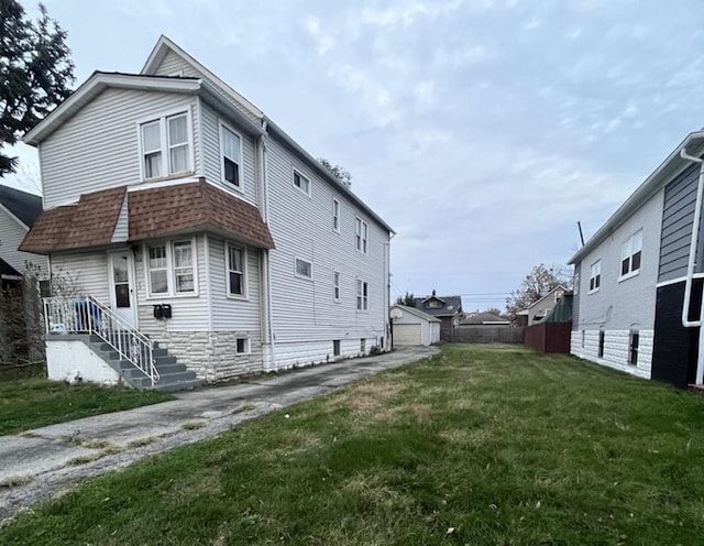 view of side of home with a garage, a yard, and an outbuilding