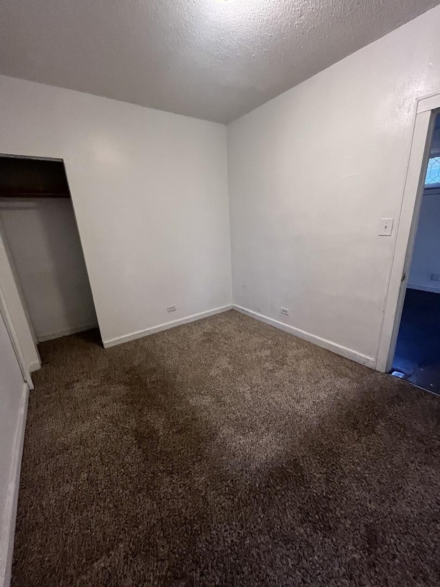 unfurnished bedroom featuring dark carpet and a textured ceiling