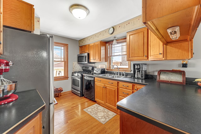 kitchen with tasteful backsplash, sink, stainless steel appliances, and light wood-type flooring