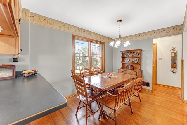 dining space featuring a notable chandelier and light wood-type flooring