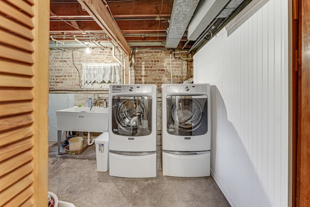 washroom featuring washing machine and clothes dryer and brick wall