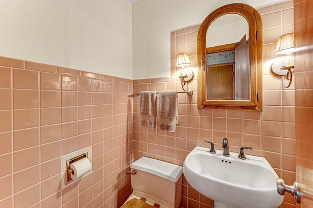 bathroom with toilet, tile walls, and sink