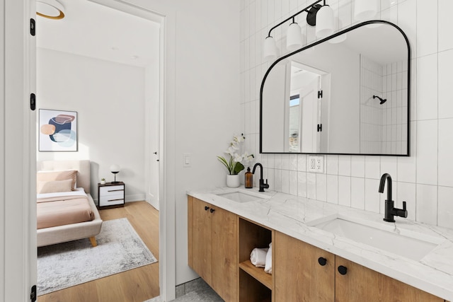 bathroom with hardwood / wood-style floors, vanity, walk in shower, and backsplash